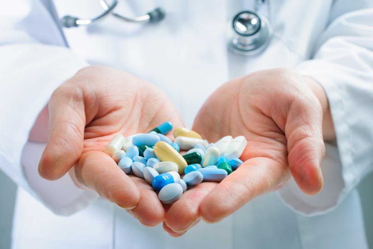 Ruky doktora držiace mnoho rôznych tabletiek