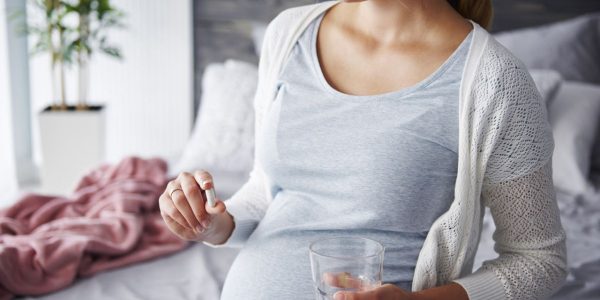 mladá tehotná žena si podáva tabletku